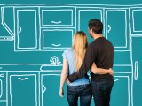 Happy embracing couple planning their home kitchen furnishing renovation.